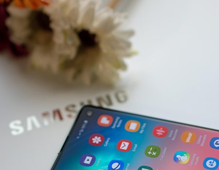 Samsung One UI 8 beta has launched. Picture shows a Samsung mobile phone on a Samsung laptop screen with some flowers in the background