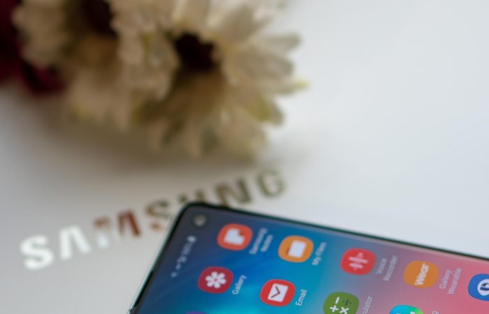 Samsung One UI 8 beta has launched. Picture shows a Samsung mobile phone on a Samsung laptop screen with some flowers in the background