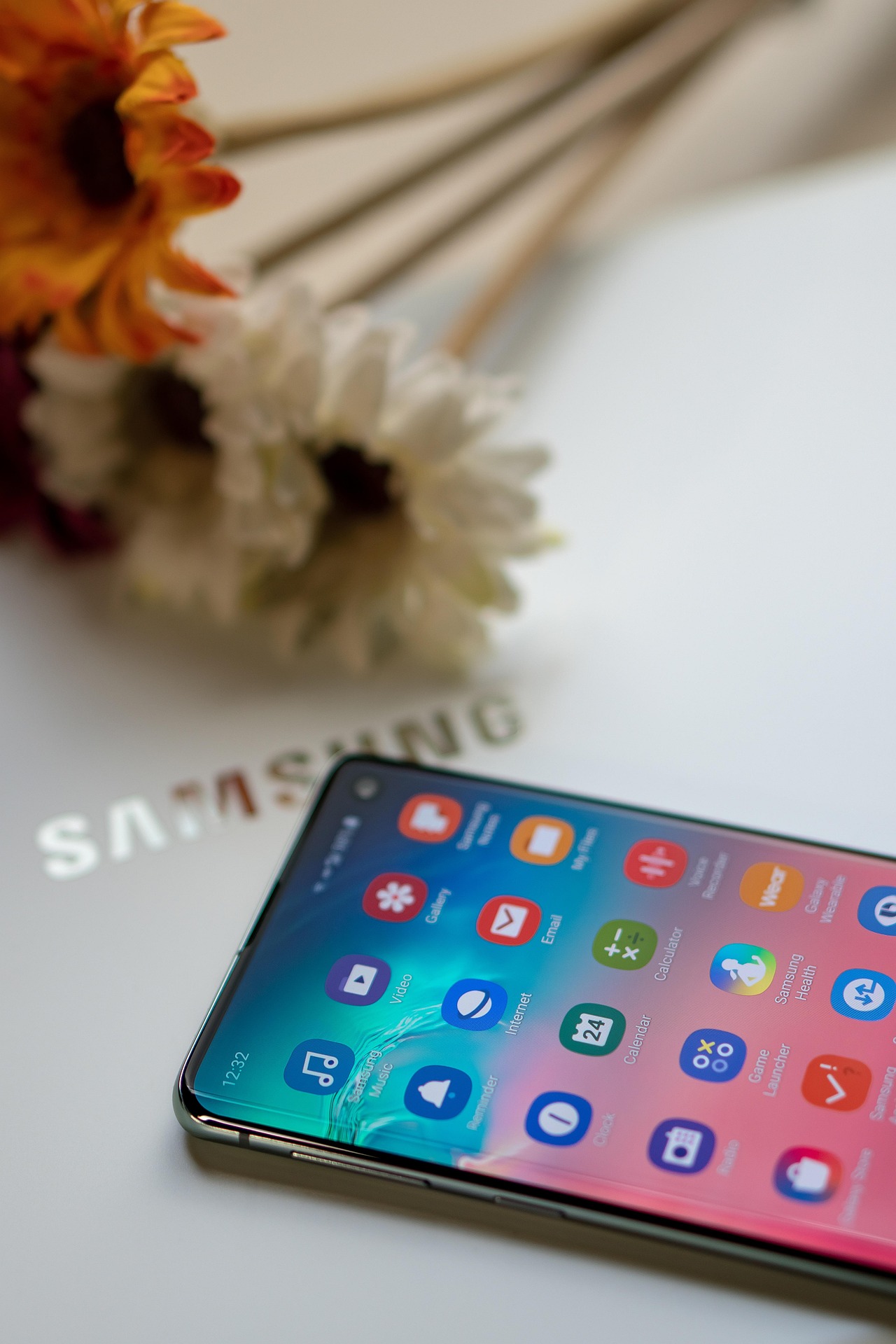 Samsung One UI 8 beta has launched. Picture shows a Samsung mobile phone on a Samsung laptop screen with some flowers in the background