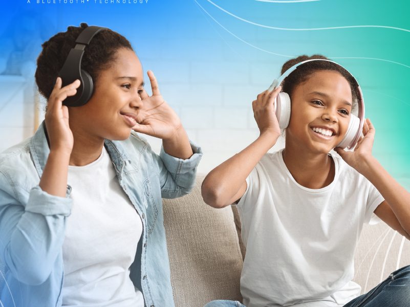 Two girls joyfully listening to music with auracast bluetooth headphones