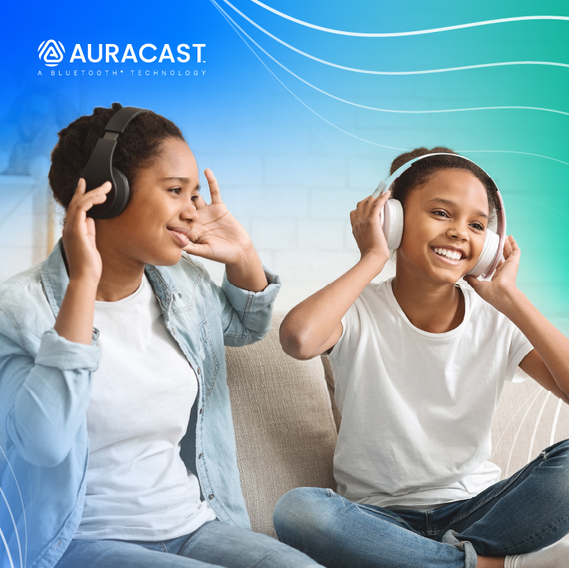 Two girls joyfully listening to music with auracast bluetooth headphones