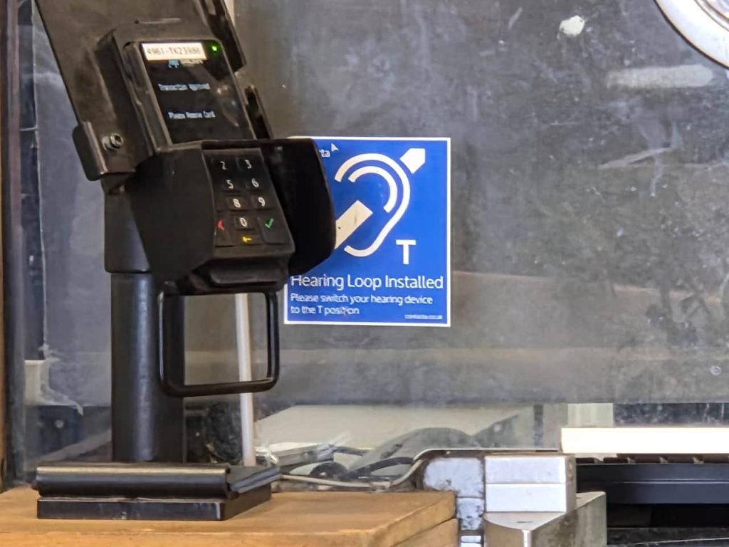 A telecoil sign hidden behind a credit card machine at Bristol Temple Meads station