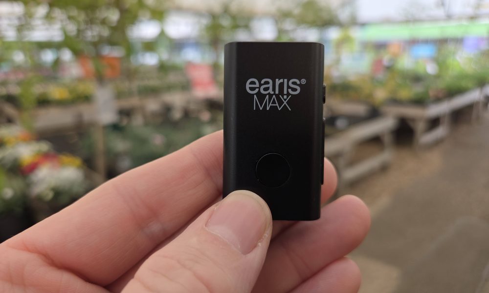 EARISMax Microphone takes Auracast anywhere – it’s small, mighty and powerful  earisMAX Auracast streaming microphone held between finger and thumb in a garden centre