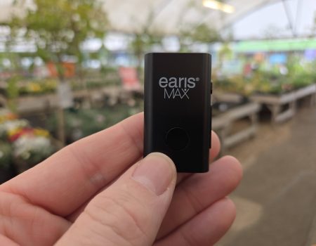 EARISMax Microphone takes Auracast anywhere – it’s small, mighty and powerful  earisMAX Auracast streaming microphone held between finger and thumb in a garden centre