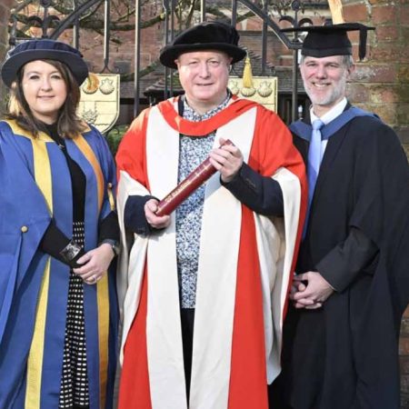 The University of Reading presented an honorary degree to Phil Creighton (pictured centre). All three people are wearing ceremonial robes for an academic institution.