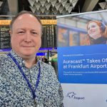 Phil Creighton at Frankfurt Airport next to a banner announced the launch of Auracast