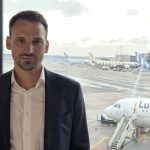 Johannes Sittig looking at the camera, with aeroplanes behind him