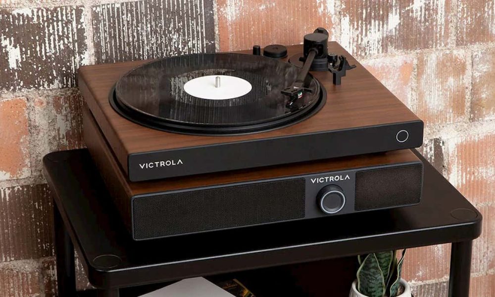 Victrola Soundstage sitting on top of a table. It is a speaker system with a turntable on top of it. Behind it is a brick wall
