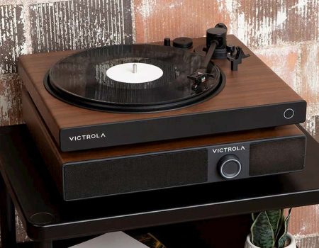 Victrola Soundstage sitting on top of a table. It is a speaker system with a turntable on top of it. Behind it is a brick wall