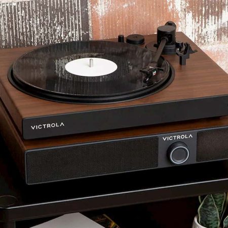 Victrola Soundstage sitting on top of a table. It is a speaker system with a turntable on top of it. Behind it is a brick wall